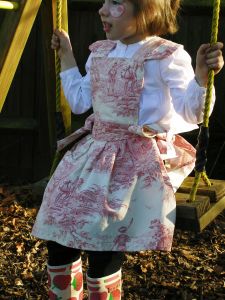 The very finest traditional thick French fabric in soft white & dusky pink with scenes of traditional French children.
Finished with hand tied side bows and scalloped edge fine stitching.
All pinafore dresses are available in all of our swatches and can be worn over jeans and a long sleeve top for a more casual look or equally worn underneath our co-ordinating Tutu. 
Machine Washable
Ages 2-8 years Price: &pound;34.50