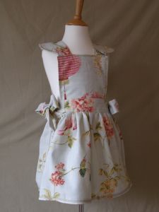 Our French & Floral "Raphi" pinafore dress is beautiful.  Made with English floral fabric in palest green with large peony rose heads, birds Of paradise and Chinese lanterns. 
Finished with hand tied side bows and scalloped edge fine stitching.
All pinafore dresses are available in all of our swatches and can be worn over jeans and a long sleeve top for a more casual look or equally worn underneath our co-ordinating Tutu.
Machine Washable
Ages 2-8 years Price: &pound;34.50
