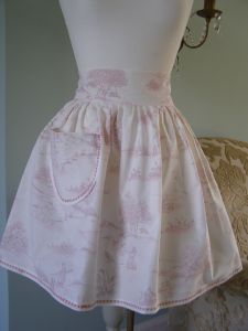 Our Pink Toile French apron is Pretty. Made with generous amounts of gather and a deep, high waistband. Every Pink Toile apron has been made with a large front pocket and a long wide tie to the rear. Finished with fine scalloped edge contrasting stitching. (Pink Toile girls co-ordinating pinafore dress available). Cotton. Fully Machine Washable. 
 Price: &pound;35.25